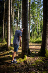 Mann über 50 stützt sich mit der Hand an einem Baum ab. Depression, Herbst, alleine.