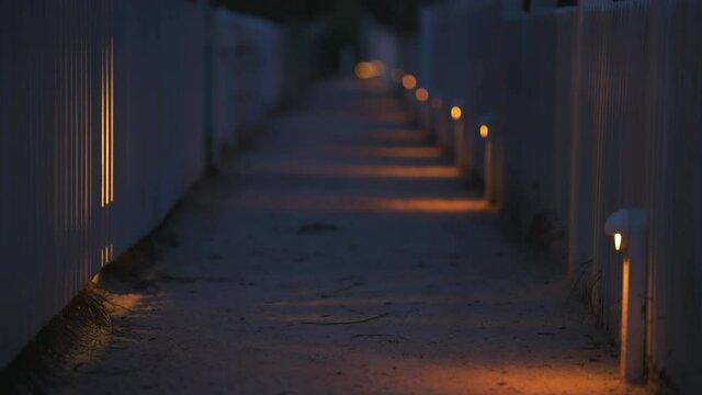 Focus rack of white beach wooden architecture with path way at dark night evening lamps lights row by vacation rental property houses buildings