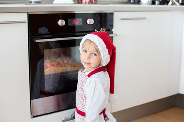 Cute blond child, boy and his mom, baking christmas cookies at home