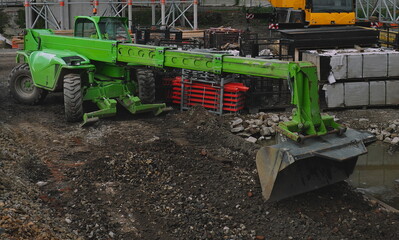 excavator, construction car manita with a bucket at work, green color, clay and construction...