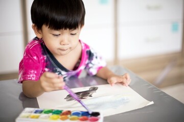 Little asian boy painting with watercolor