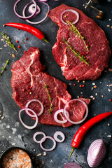 Two raw steak New York with rosemary and spices on a piece of parchment paper on old dark stone background. Top view. Mock up.
