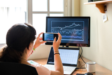 Female trader shooting stock graphs while working from home.
