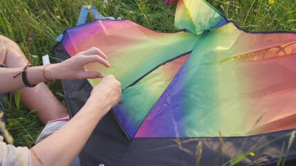 4K  close up piercing his kite with needle attaching rope to it before flying. Entertainment, spending time outdoors, handmade concept.