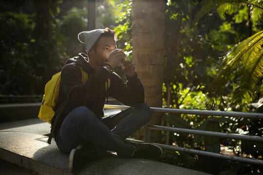 Black man drinking takeaway coffee in city park