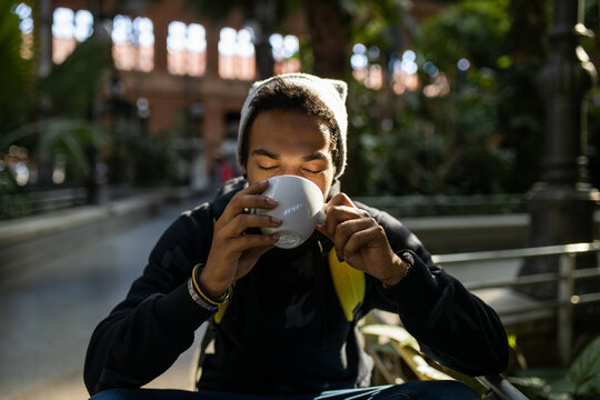 Black man drinking takeaway coffee in city park