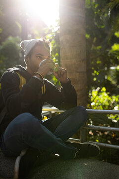 Black man drinking takeaway coffee in city park