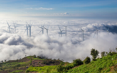 Wind turbines for generate clean energy on mountain hill covered by sea of fog on morning.