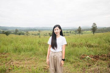 Happy traveler hipster girl with windy hair smiling, standing on top of sunny mountains. space for...