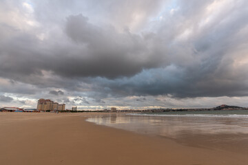 The sky is covered with dark clouds and the beach is cloudy