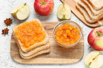 Bread toast with apple jam in jar on wooden cutting board