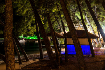 Makarska, Croatia,  Night view of the illuminated boardwalk and a small tikki bar.