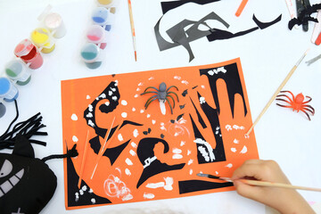 Child making card for the holiday of halloween. Funny crafts from pieces paper. Halloween decor. The concept for Halloween. DIY. Children's art project, a craft for children.