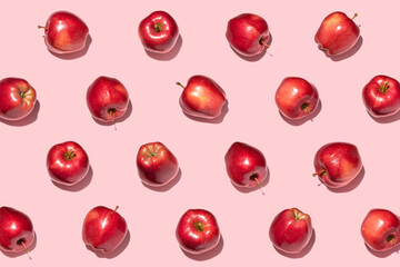 Red apples on pink background. Pattern, top view, flat lay.