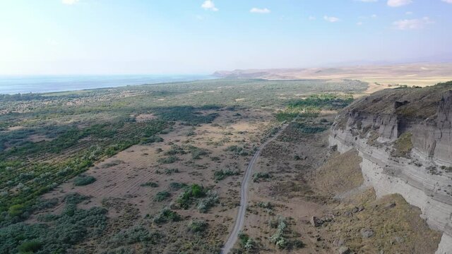Aerial view road near sand mine. Aerial footage road between field with dry grass and small trees.  It's located near Sevan Lake, Armenia, Caucasus. 