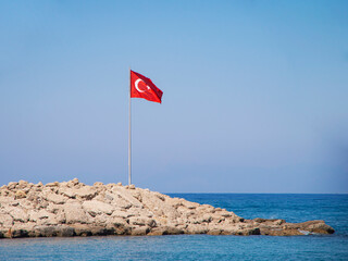 flag on the beach. Turkey flag against the background of the turquoise Mediterranean sea and blue sky set in the seaport of Antalya, Turkey