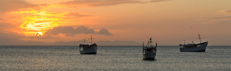 Fototapeta na wymiar Boats at sea, backlit, at sunset time