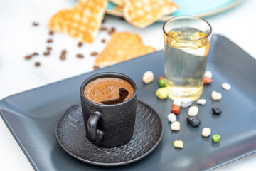 Traditional turkish coffee in a modern black cup with water and sugar. Selective focus