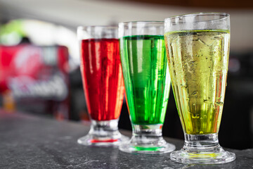 Three multi-colored cocktails: red, yellow and green on the bar. Summer vacation concept
