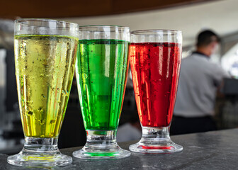 Three multi-colored cocktails: red, yellow and green on the bar. Summer vacation concept
