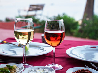 wine in a restaurant. Two Glasses of white and rose Wine on the table of a restaurant, Alcoholic drink on a served set table on a background of the Beach. Transparent wine on the summer terrace 