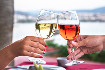 two glasses of wine. Festive Toast, Two Glasses of red and white Wine in the hands of a couple, during a romantic date