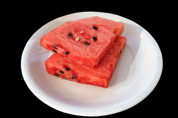Slices of watermelon on a white plate on a dark background