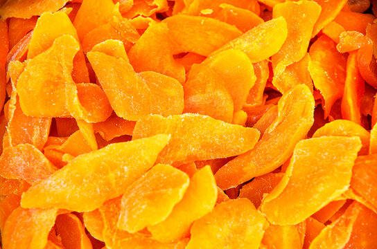 Candied fruits, mango pieces. Background from orange dried mangoes with texture effect Heap of candied slices, crystallized fruit, food background, close-up, soft selective focus