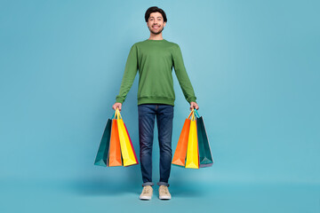 Full body photo of good looking smiling male hold shopping bags shopaholic black friday isolated on blue color background