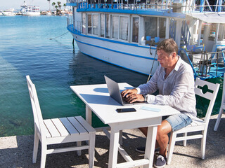 Man with laptop  on the beach is working. Social distancing in quarantine, networking, work online,...