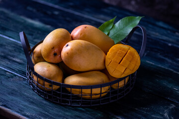 Cut and intact mangoes in the dark background