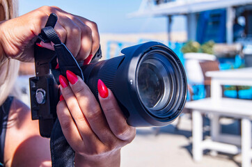 camera in hand. Young woman using a DSLR camera. close-up of hands Women - professional photographer with camera outdoors.