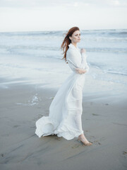 Fototapeta na wymiar Woman in white dress walking barefoot on the sand ocean fresh air travel