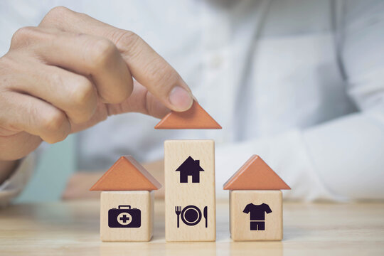 The investor's hand placed a wooden cube with word Work, Planning to buy property concept ,food Clothing, housing, medicine, four basic human needs concept.