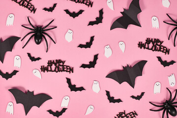 Halloween flat lay with bats, spiders, Happy Halloween text and cute ghosts on pink background