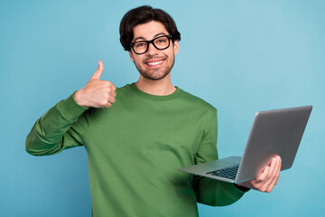 Portrait of smiling geek nerd young businessman in glasses show thumb-up hold laptop isolated on...