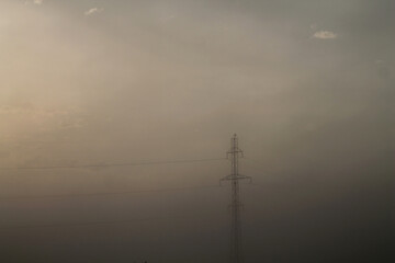 Power lines at sunrise.Power lines at sunrise. Country road at dawn in the fog
Power lines at dawn in the fog. Fog over the field