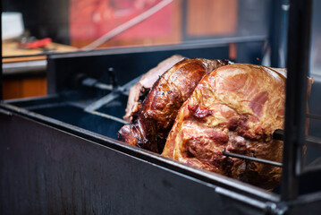 Roasted smoked pork leg ham grilling in street food market at Prague, Czech Republic.