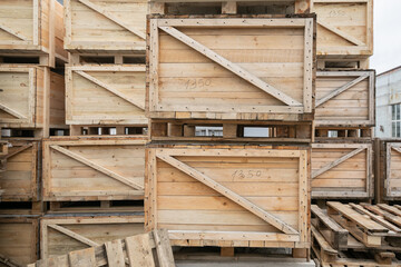 A stack of huge wooden crates in a storage area. Big boxes of goods in an open-air warehouse awaiting transportation. Logistics and distribution concept