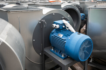 Batch of industrial exhaust snail fans with installed electric motors for air ventilation in a factory open-air warehouse storage area awaiting transportation.