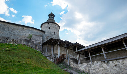 The fortress wall of a medieval fortification with towers against a bright blue sky. © eskstock