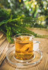 Teacup with bag on wooden table in front of blurred nature background of flovers and leaves. Bokeh concept