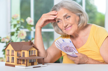 Portrait of elderly woman with euro bills and house