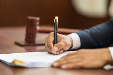Closeup of judge wooden gavel on sounding block and man handwriting on the background. The legal...