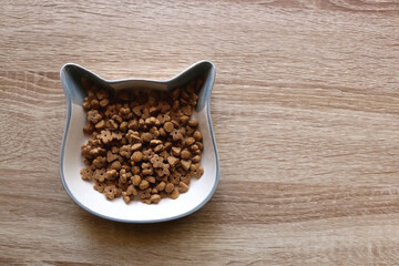 Cat shaped bowl filled with dry cat food. Top view.