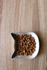 Cat shaped bowl filled with dry cat food. Top view.