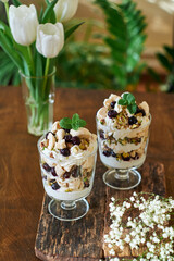 Eton Mess. Trifle with meringue, blueberries, pistachios and mint. Dessert in a glass. Side view. Wooden background.
