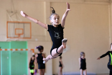 Girl gymnast jumping the splits on training in gym