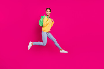 Fototapeta na wymiar Photo of adorable sweet young woman dressed yellow pullover backpack jumping smiling isolated pink color background
