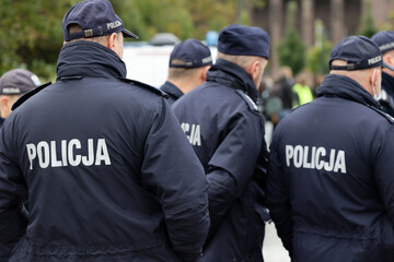 Polscy policjanci w niebieskim mundurze na zabezpieczeniu imprezy w mieście.